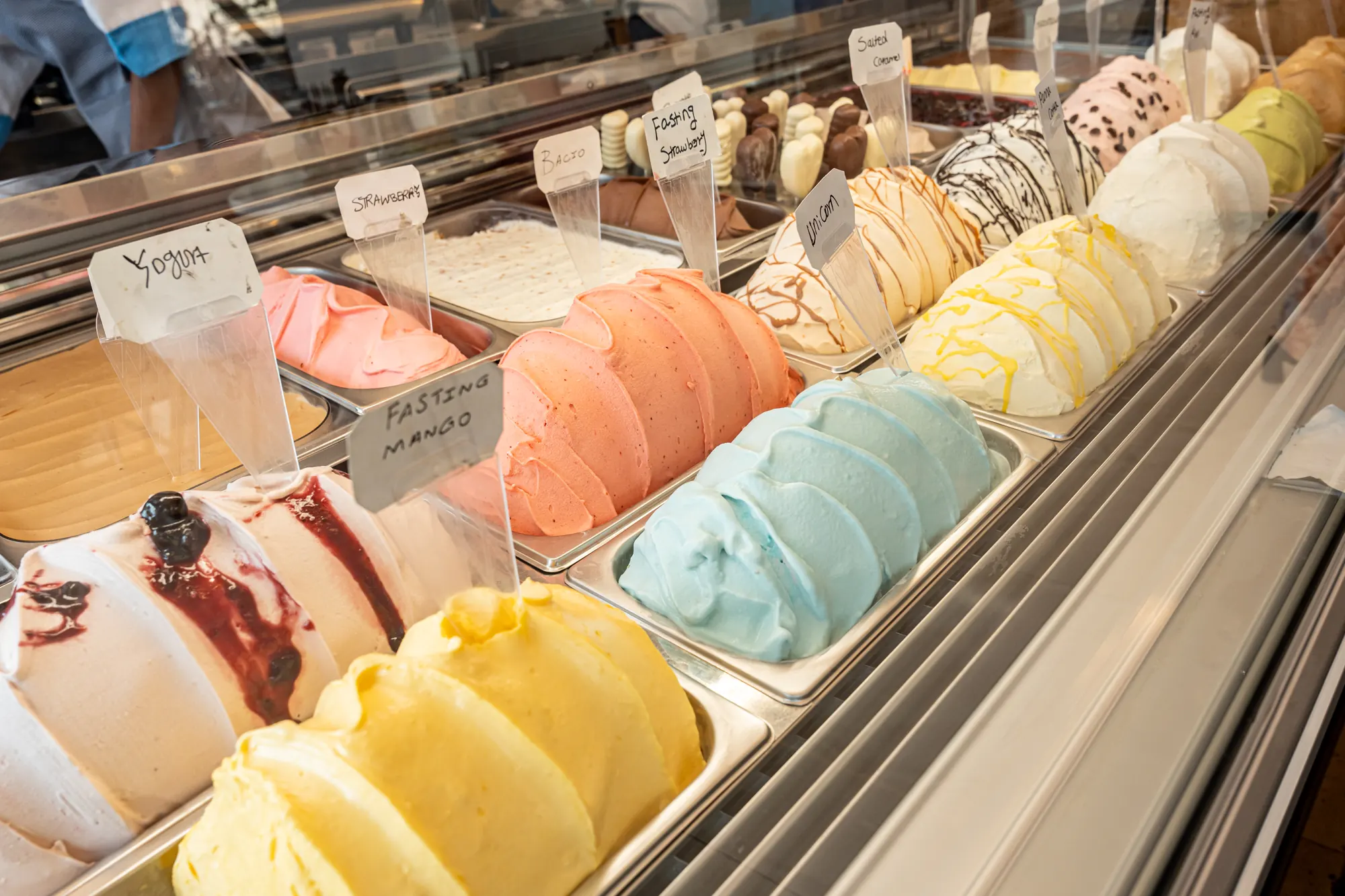 Gelato flavours in the display case, each with a handwritten label
