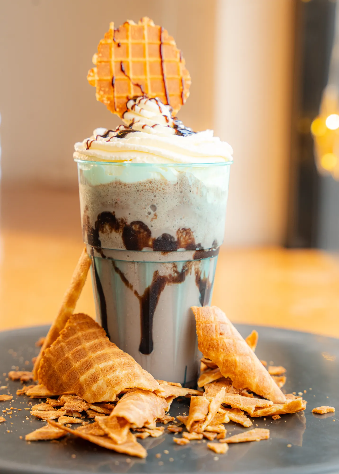 A chocolate milkshake with whipped cream, a wafer crisp and broken cones