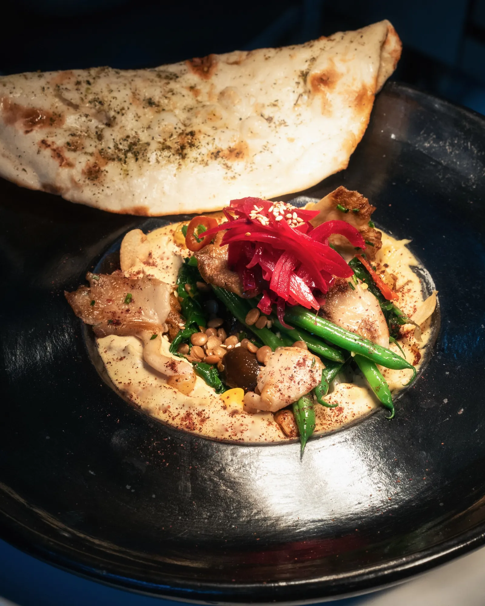 Grilled chicken, green beans and pickled onion on hummus, with flatbread