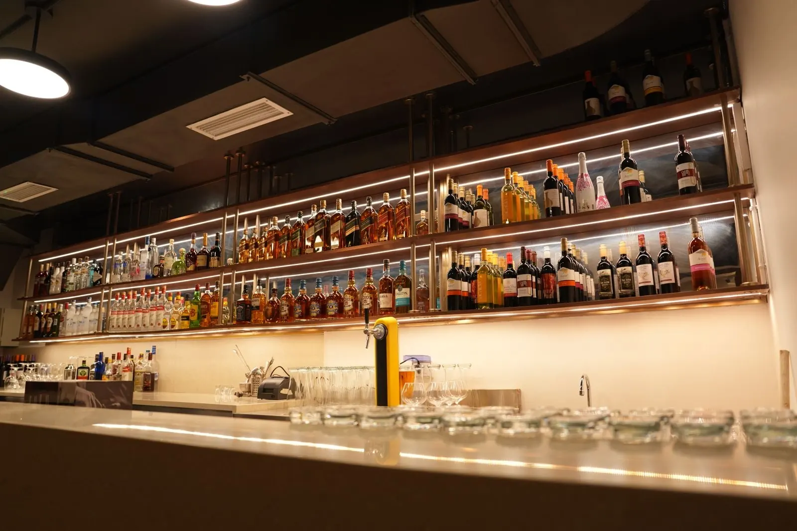 Backlit bar shelves stocked with wines and spirits