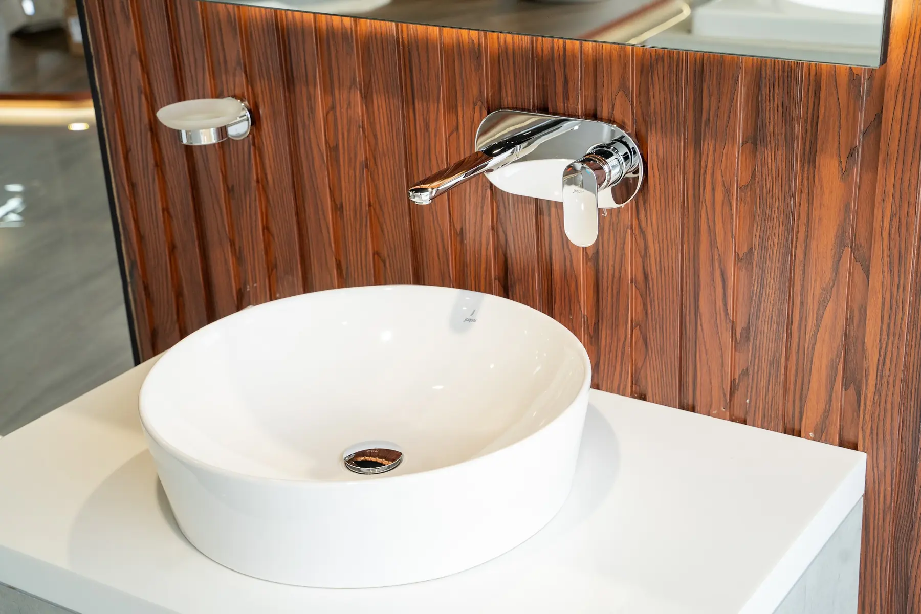 A round vessel basin under a wall-mounted mixer