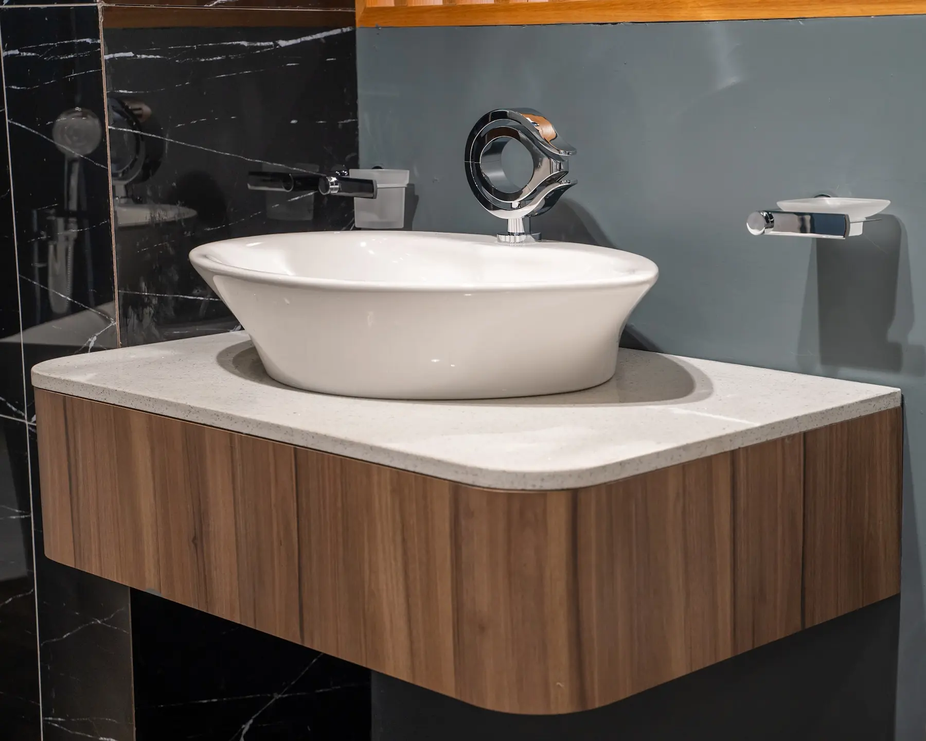 A white vessel basin on a curved walnut vanity