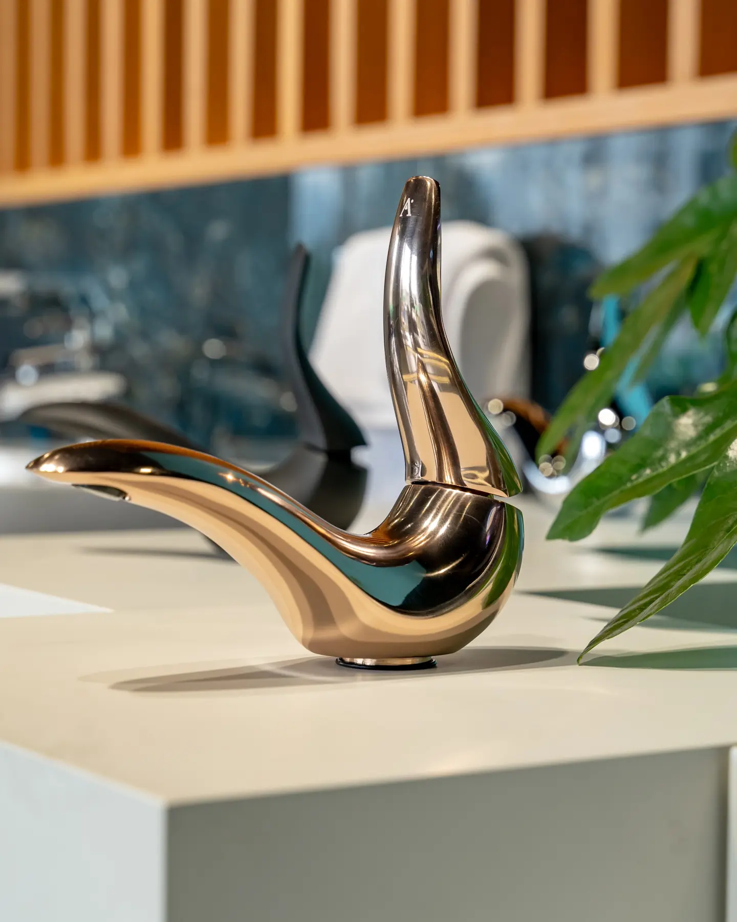 A sculptural rose gold faucet with a curved spout