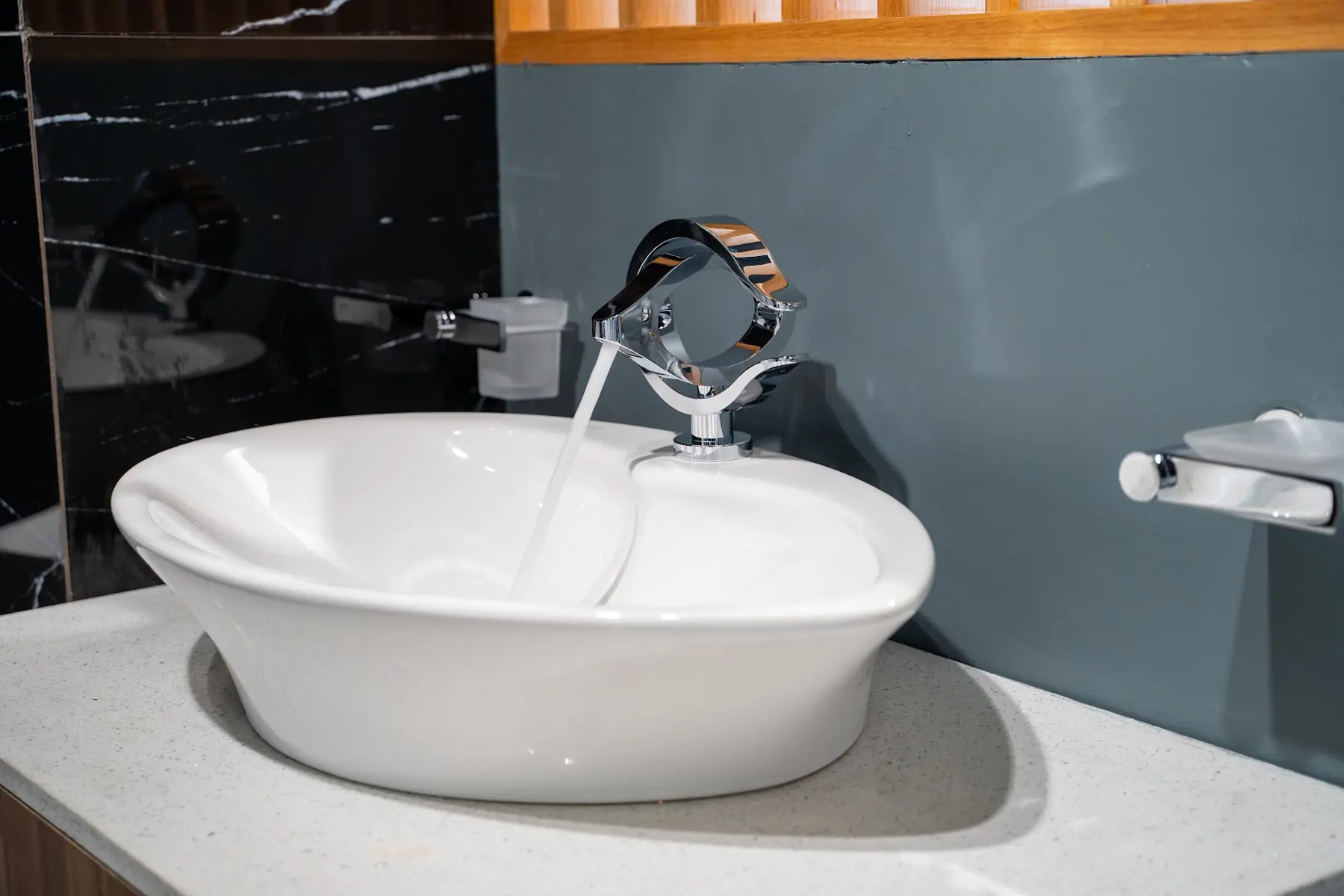 Water running from a chrome faucet into a vessel basin