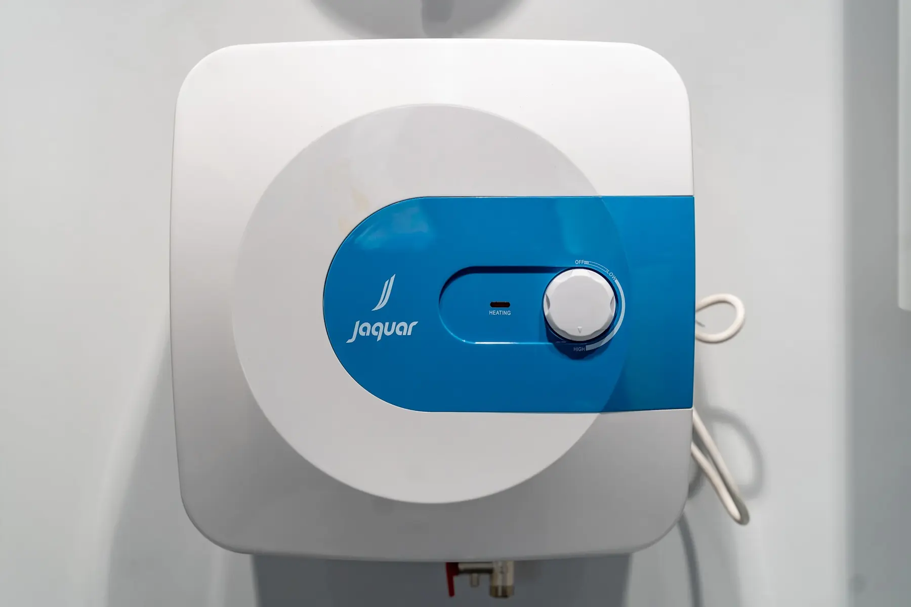A compact square water heater with a blue control dial