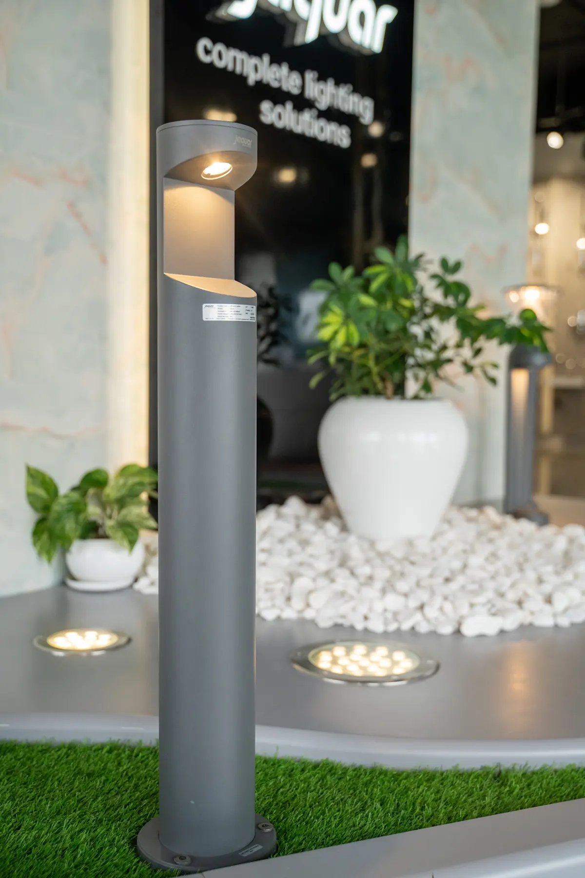 A garden bollard light beside white pebbles