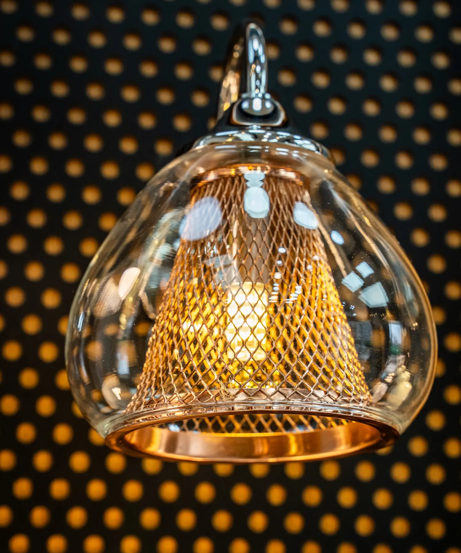 A glass pendant with a copper mesh shade